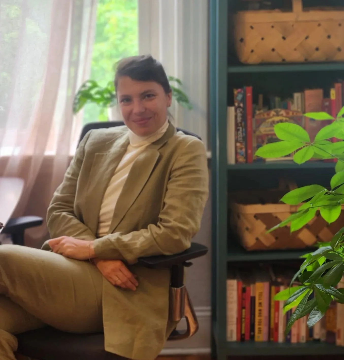 Masha Kartashev seated at her desk with bookshelves and plants in the background